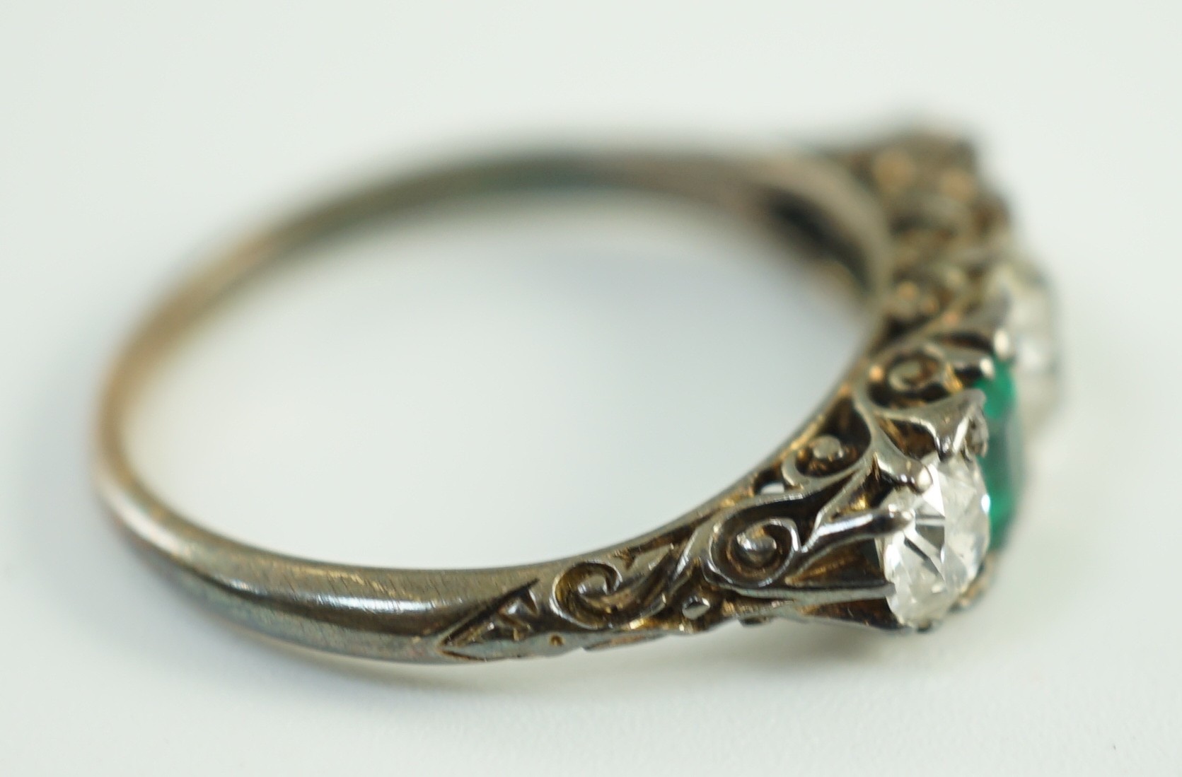 An early 20th century 18ct gold, three stone diamond and two stone emerald set half hoop ring